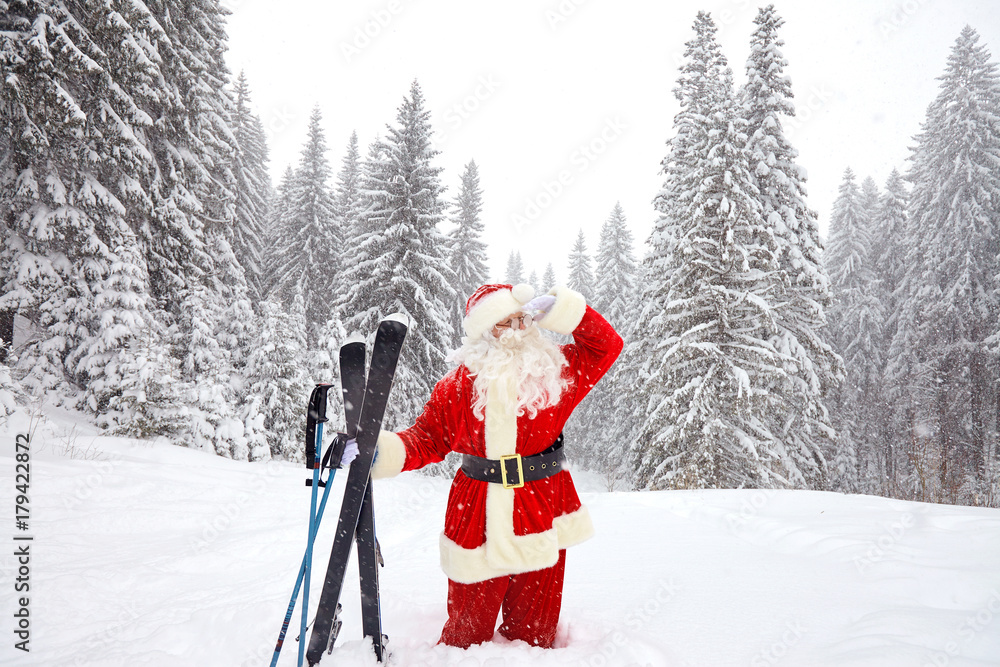 Santa Claus skier with skis in the woods in winter on snow at Christmas.