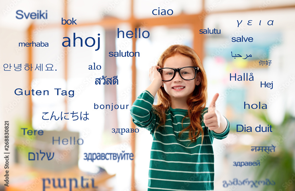 education, translation and learning concept - smiling red haired student girl in glasses and green striped shirt over greeting words in different foreign languages on background